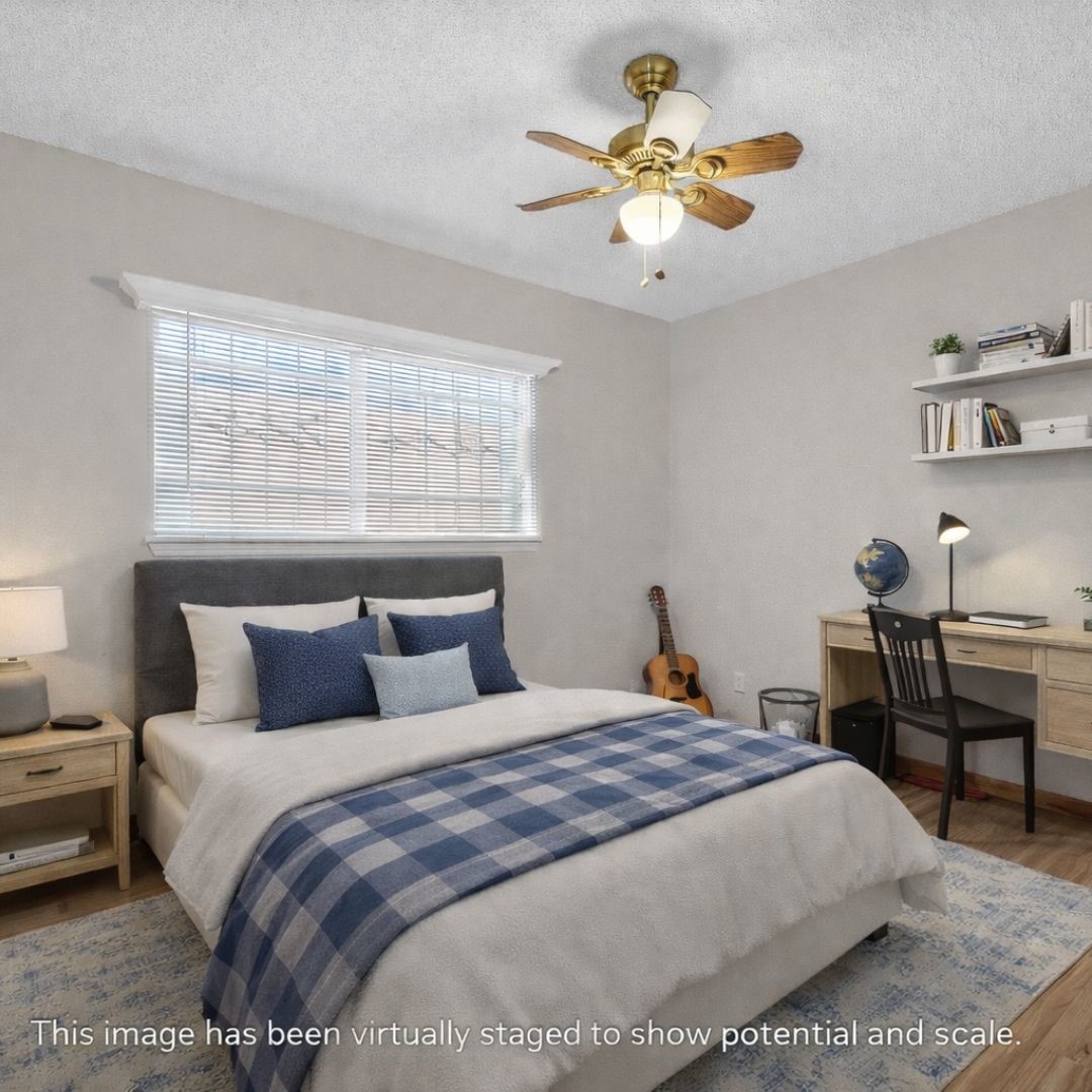 11803 Inga Lane Houston, TX 77064 - Photo 34 of 39 This cozy bedroom features a double bed with a gray headboard and blue accents. It includes a wooden desk with a chair, a shelf, and a ceiling fan. Natural light streams through a large window, creating a bright and inviting atmosphere.
