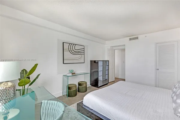 a bedroom with a bed a couch and a potted plant
