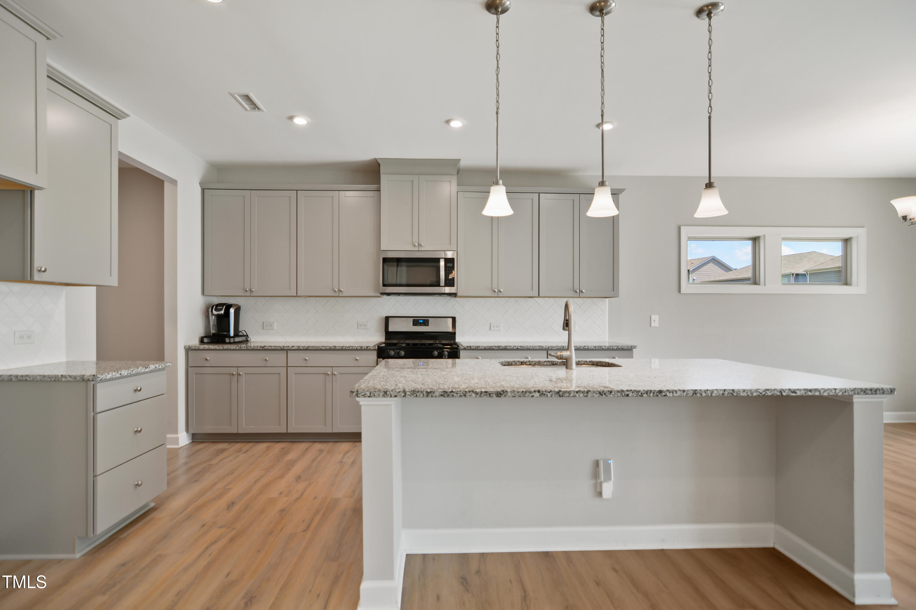 917 Lippincott Road Durham, NC 27703 - Photo 11 of 30 a kitchen with stainless steel appliances granite countertop a sink a stove a refrigerator and white cabinets with wooden floor