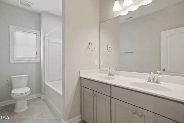 a bathroom with a toilet a sink a mirror a vanity and window