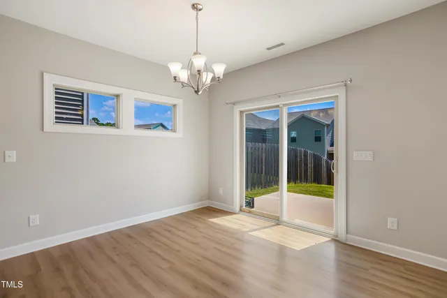 a view of an empty room with window and wooden floor