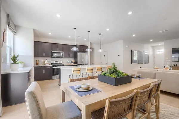 a kitchen with stainless steel appliances kitchen island granite countertop a stove a sink a dining table and chairs