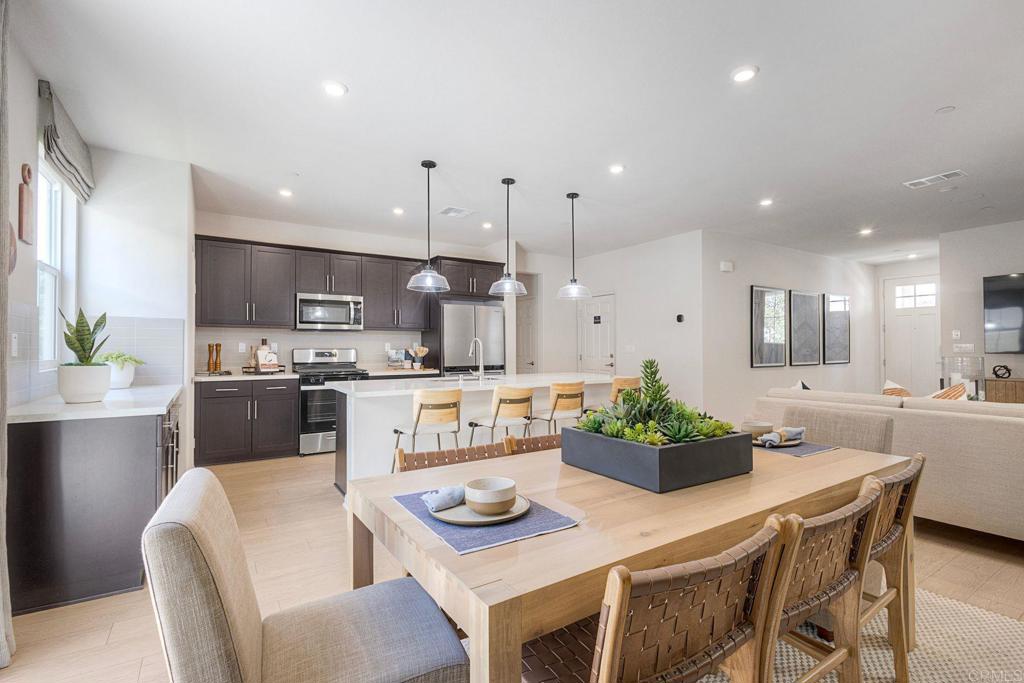 a kitchen with stainless steel appliances kitchen island granite countertop a stove a sink a dining table and chairs