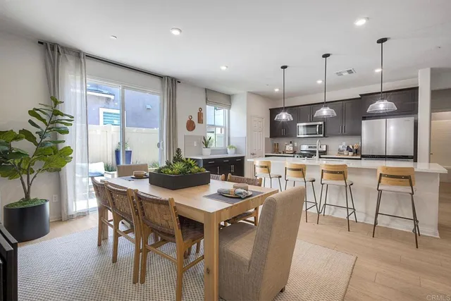 a kitchen with stainless steel appliances kitchen island granite countertop a table chairs and a refrigerator