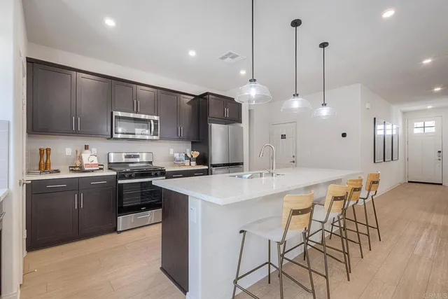 a kitchen with stainless steel appliances kitchen island granite countertop a sink a stove a dining table and chairs