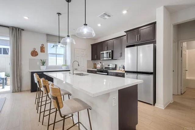 a kitchen with stainless steel appliances a table chairs refrigerator and microwave