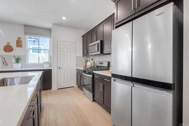 a kitchen with stainless steel appliances granite countertop a refrigerator a stove and a sink with wooden floor