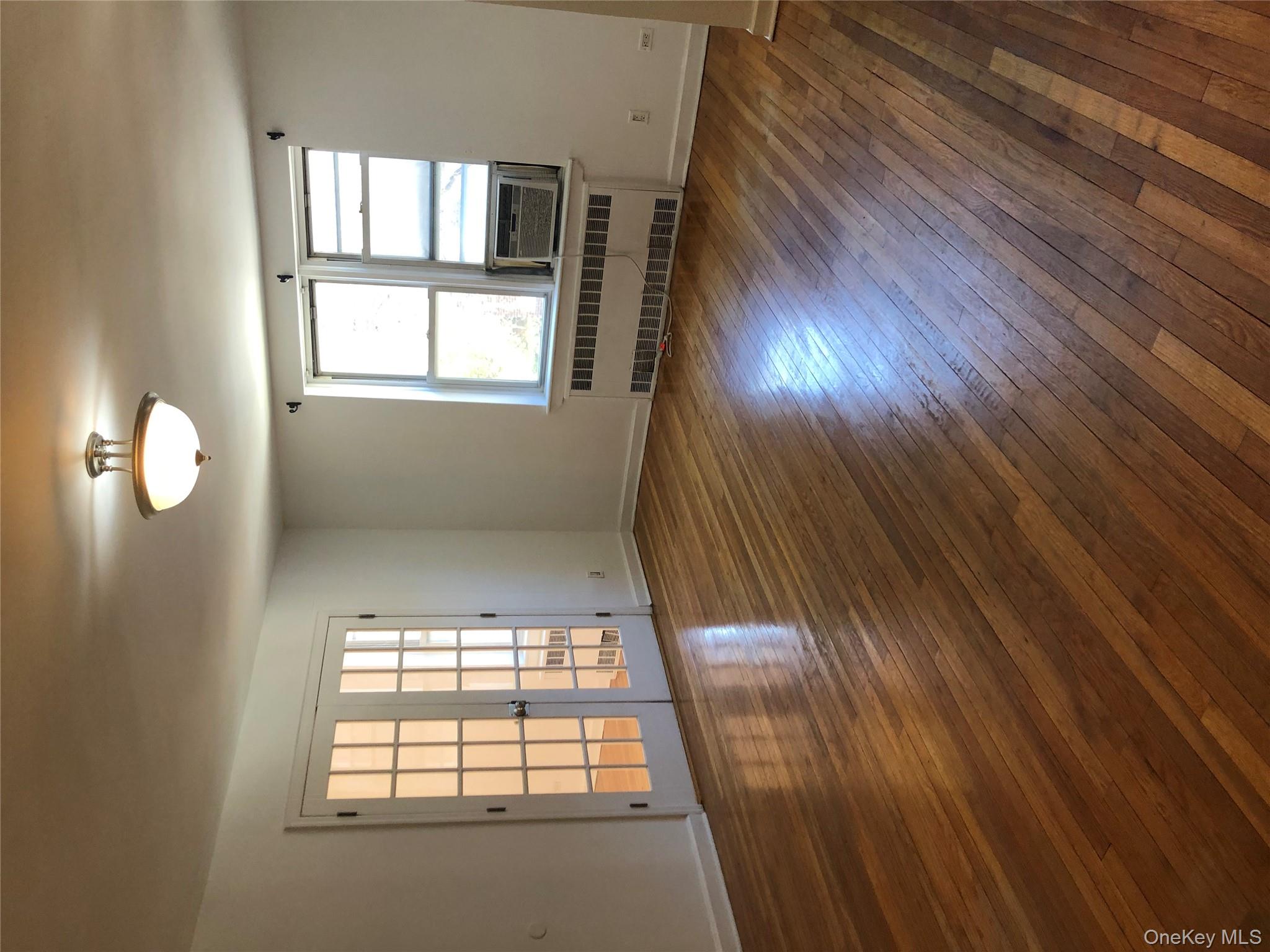 66-33 Yellowstone Boulevard, Unit 2B Queens, NY 11375 - Photo 5 of 13 an empty room with wooden floor and windows