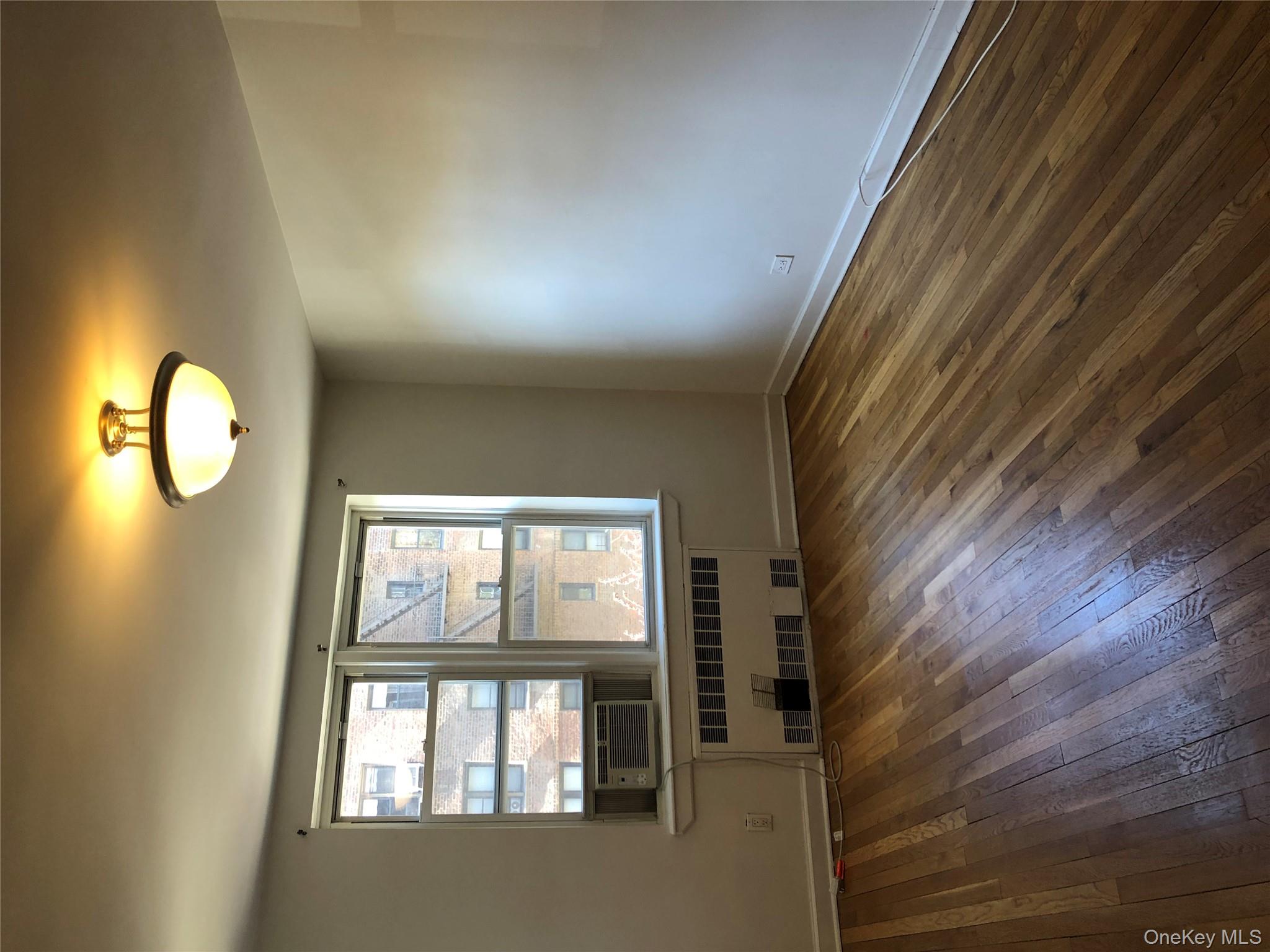 66-33 Yellowstone Boulevard, Unit 2B Queens, NY 11375 - Photo 10 of 13 an empty room with wooden floor and windows