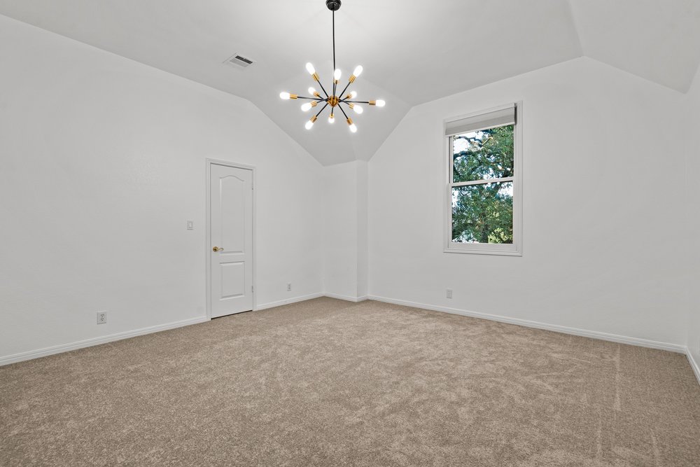 1815 Rue De St Tropez Austin, TX 78746 - Photo 36 of 40 Spacious room featuring vaulted ceilings, a contemporary sputnik chandelier, plush neutral carpeting, a single window with exterior tree scenery, and a white interior door