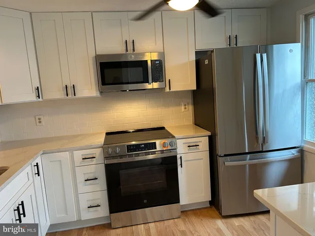 a kitchen with cabinets stainless steel appliances and wooden floor