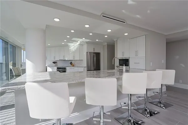 a large kitchen with stainless steel appliances kitchen island granite countertop a table and chairs in it