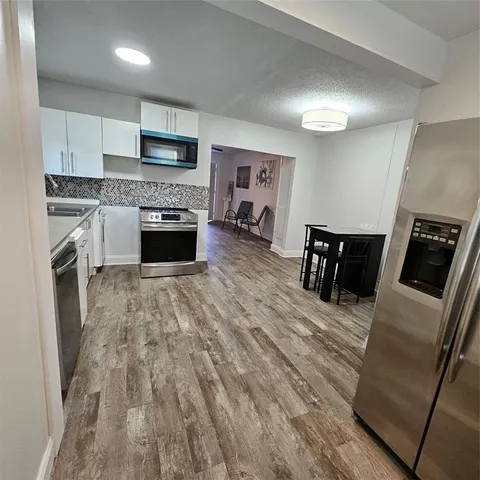 a kitchen with granite countertop a stove top oven a sink and dishwasher a refrigerator with wooden floor