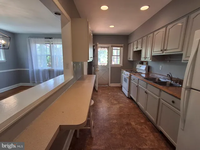 a large kitchen with kitchen island a large window a sink and stainless steel appliances