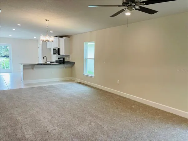 an empty room with a ceiling fan and windows