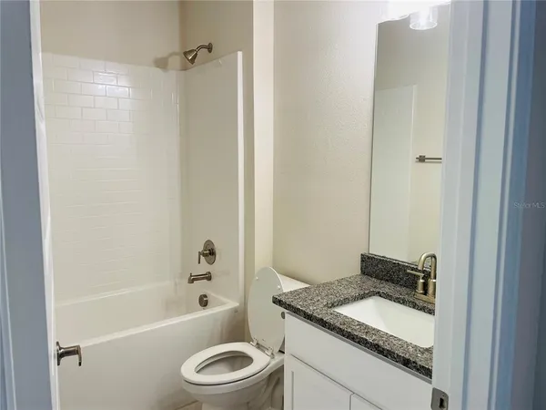 a bathroom with a granite countertop sink toilet and shower