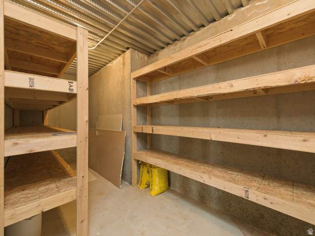6849 North Black Powder Road Mountain Green, UT 84050 - Photo 40 of 43 Extensive built-in shelving units in a concrete-walled space, featuring wood-finish shelving and a corrugated metal ceiling