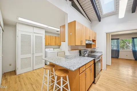 a kitchen with stainless steel appliances granite countertop a sink a stove and a wooden cabinets