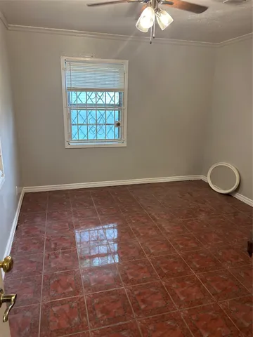 an empty room with a chandelier fan and windows