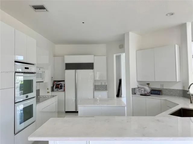 a kitchen with stainless steel appliances granite countertop a refrigerator a stove and a sink