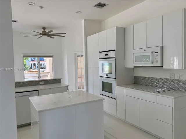 a kitchen with granite countertop white cabinets and white appliances