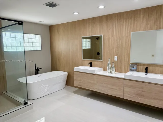 a bathroom with a double vanity sink mirror and bathtub