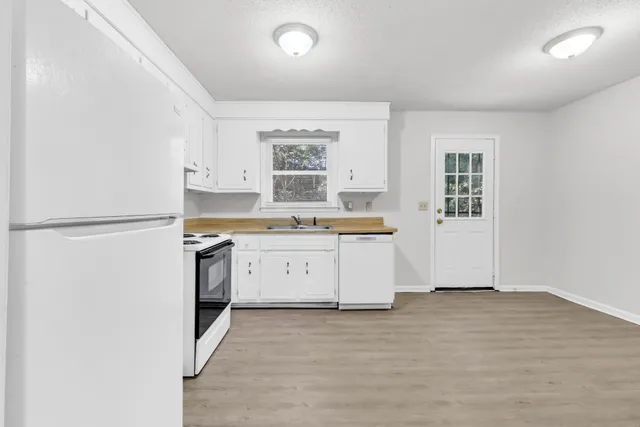 a kitchen with granite countertop white cabinets and white appliances