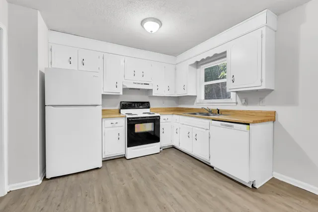 a kitchen with granite countertop a refrigerator a stove and white cabinets