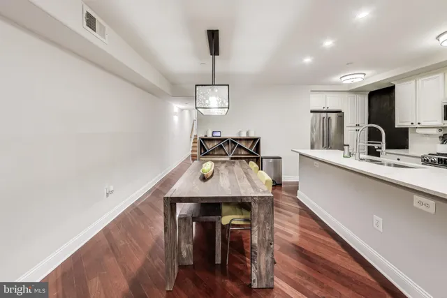a kitchen with stainless steel appliances wooden floor dining table and chairs