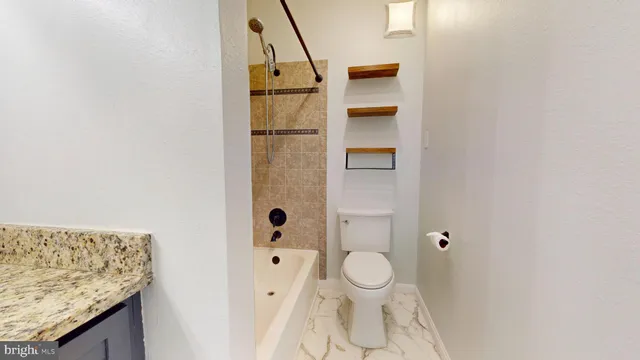 a bathroom with a granite countertop sink and a toilet