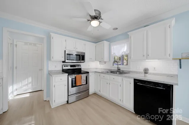 a kitchen with granite countertop a sink stainless steel appliances and white cabinets