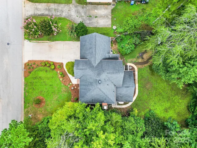 an aerial view of a house with a yard and tennis court