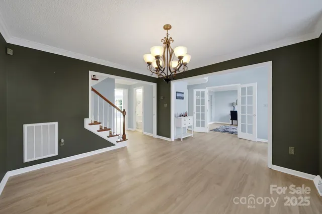 a view of a hallway with wooden floor and chandelier