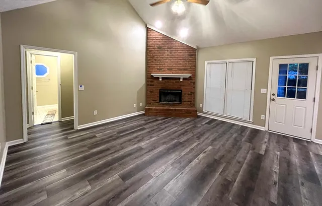 an empty room with wooden floor fireplace and chandelier