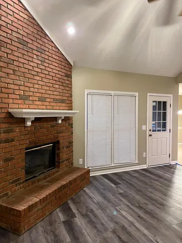 an empty room with wooden floor fireplace and windows