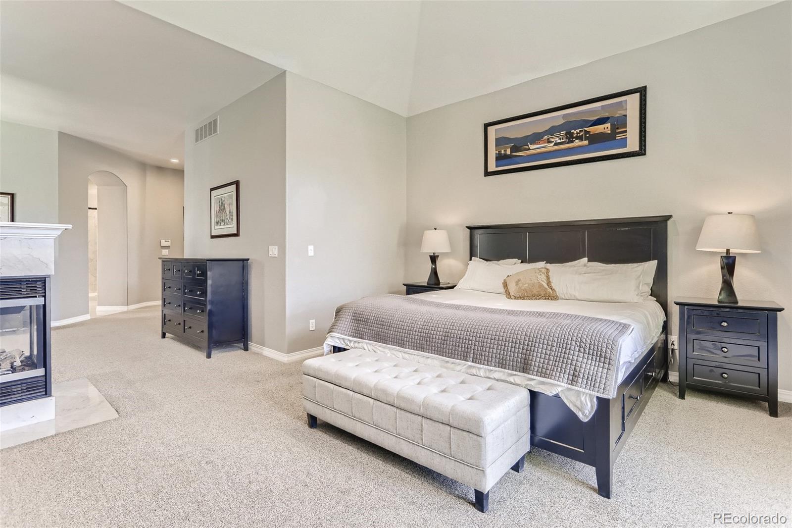 10189 Longview Drive Lone Tree, CO 80124 - Photo 18 of 40 a spacious bedroom with a bed and a fireplace