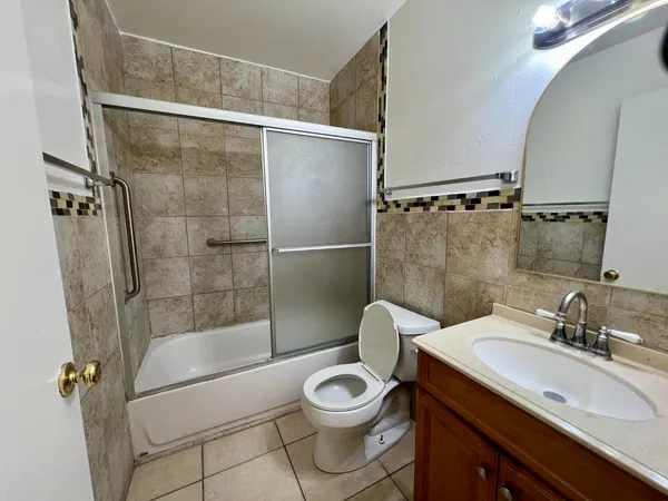 a bathroom with a granite countertop sink toilet a mirror and shower