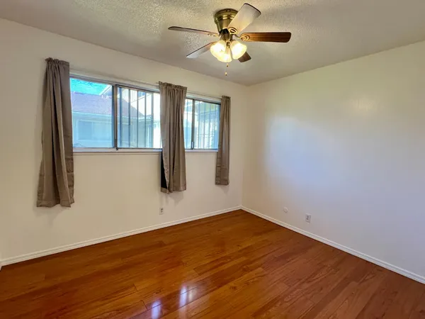 a view of an empty room with a window and wooden floor