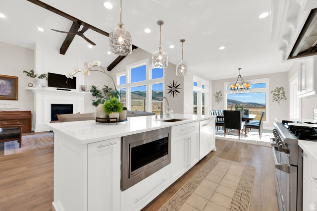 352 East Boulderville Road Oakley, UT 84055 - Photo 13 of 62 Kitchen featuring white cabinetry, range hood, a fireplace, stainless steel appliances, and vaulted ceiling