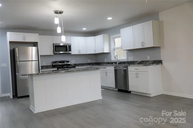 a kitchen with stainless steel appliances a sink stove refrigerator and cabinets