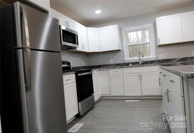 a kitchen with white cabinets stainless steel appliances and a sink