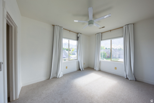 868 Braddock Lane Alpine, UT 84004 - Photo 39 of 64 Bright room featuring two large windows, a ceiling fan, and light-toned carpeting