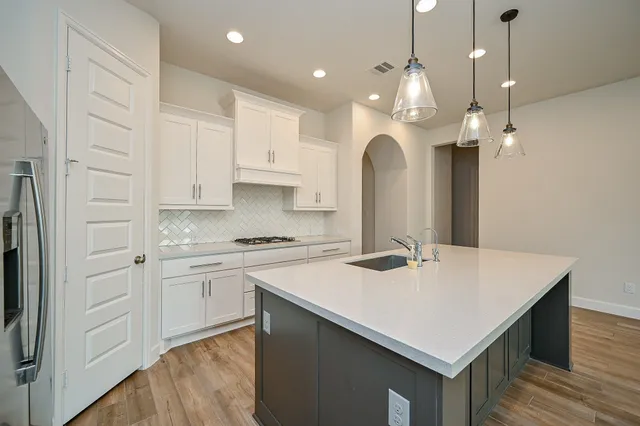 a large kitchen with stainless steel appliances granite countertop a large counter top and a wooden floors