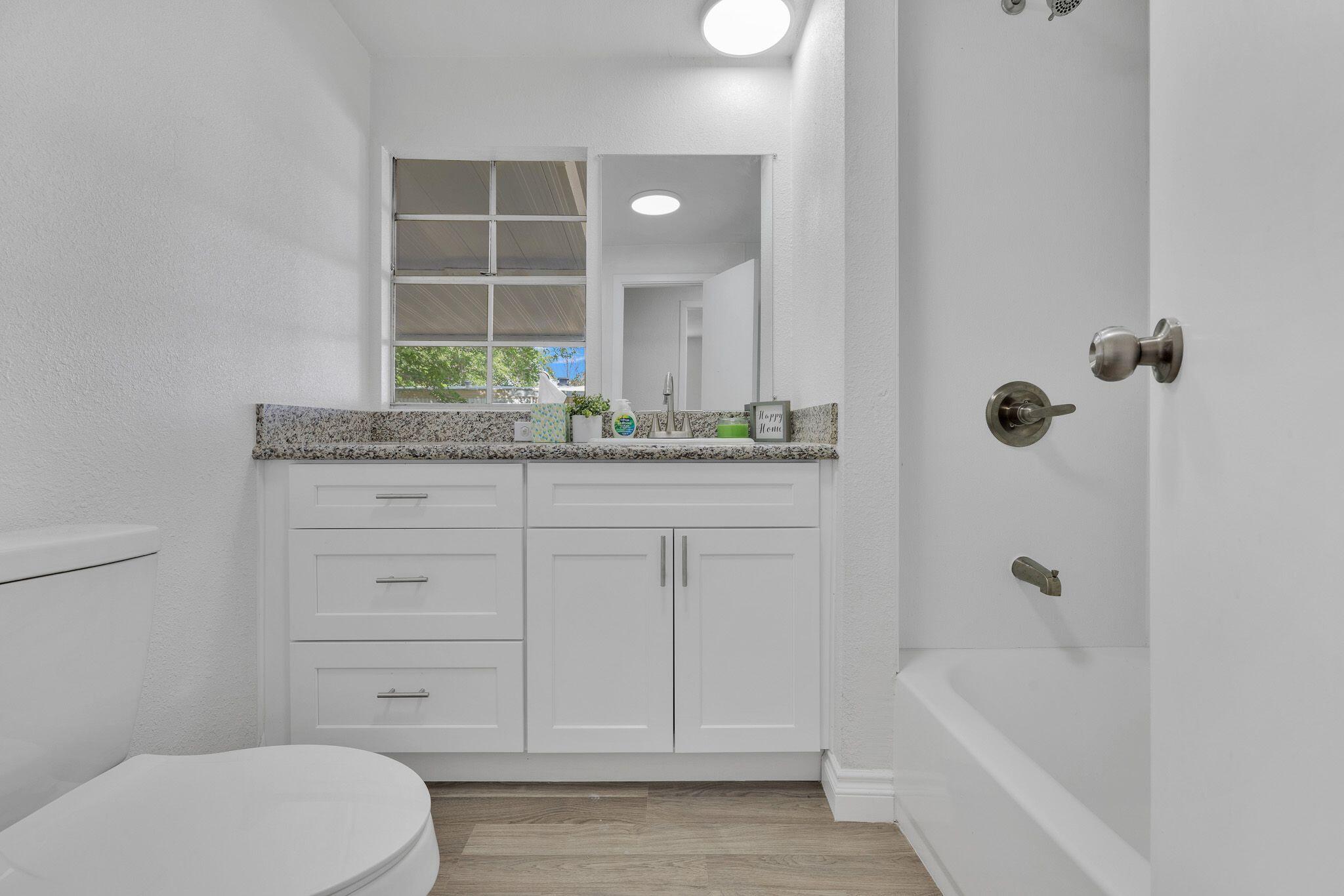 1301 East Avenue I Lancaster, CA 93535 - Photo 11 of 25 a bathroom with a granite countertop sink a toilet and bathtub