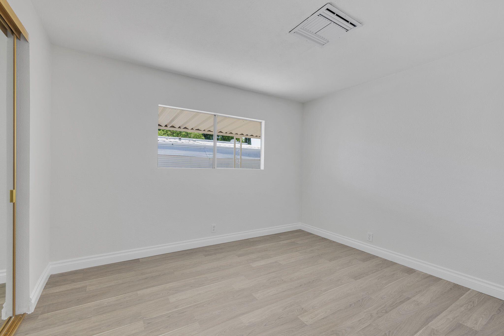 1301 East Avenue I Lancaster, CA 93535 - Photo 13 of 25 an empty room with a wooden floor and a window