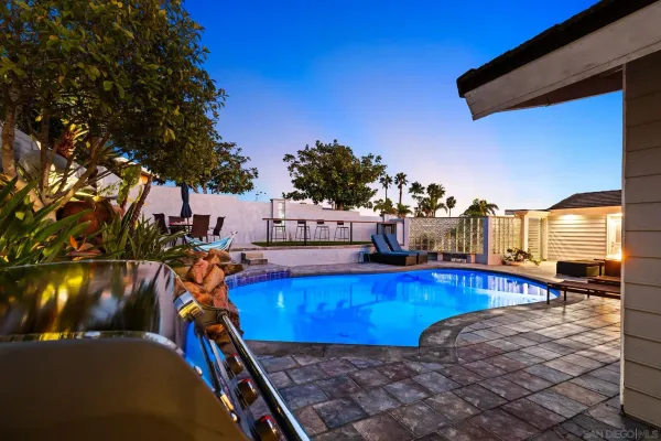 a view of a swimming pool with a chairs and table in the patio