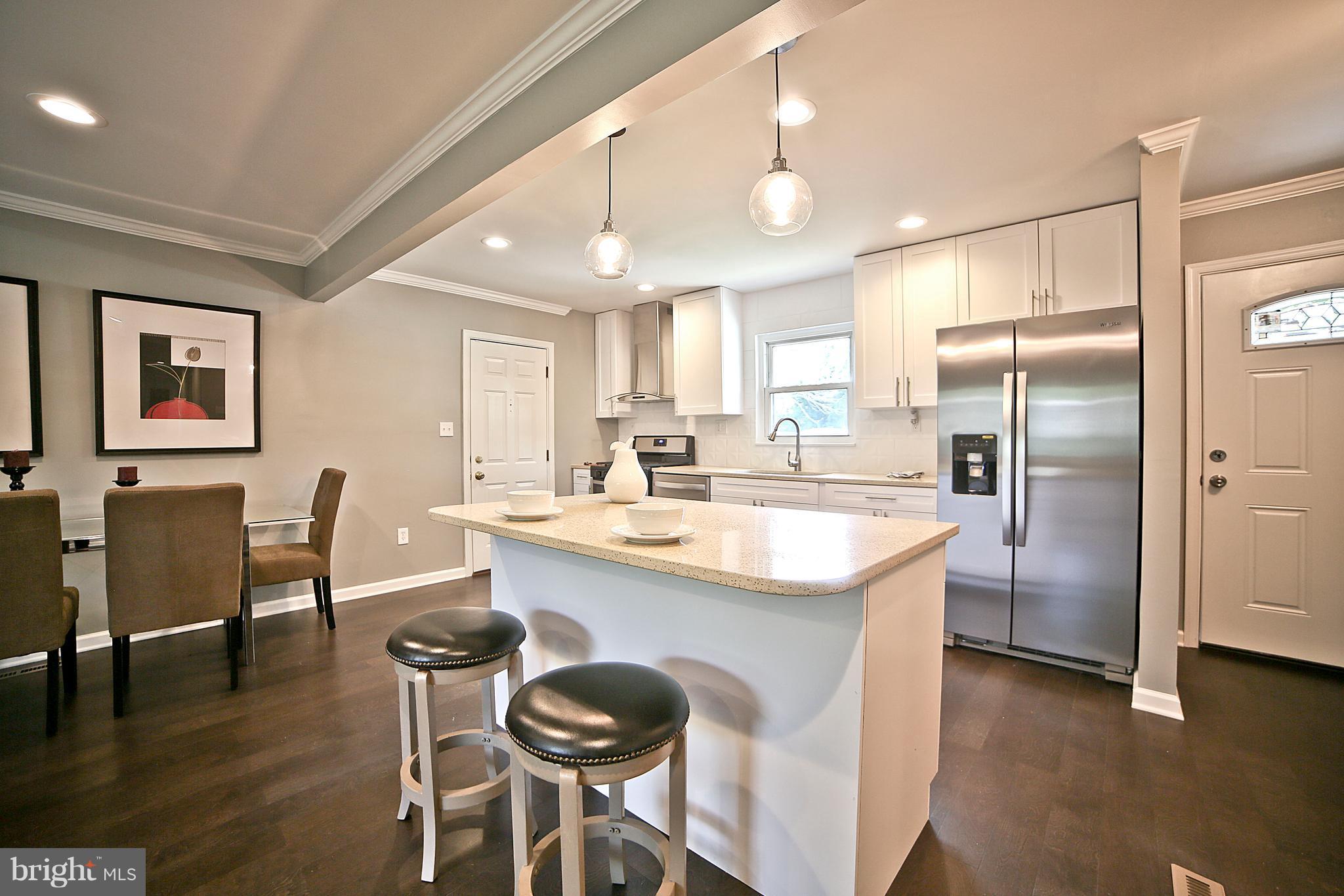 6612 Cimarron Street Springfield, VA 22150 - Photo 4 of 30 a kitchen with stainless steel appliances granite countertop a dining table chairs refrigerator and sink