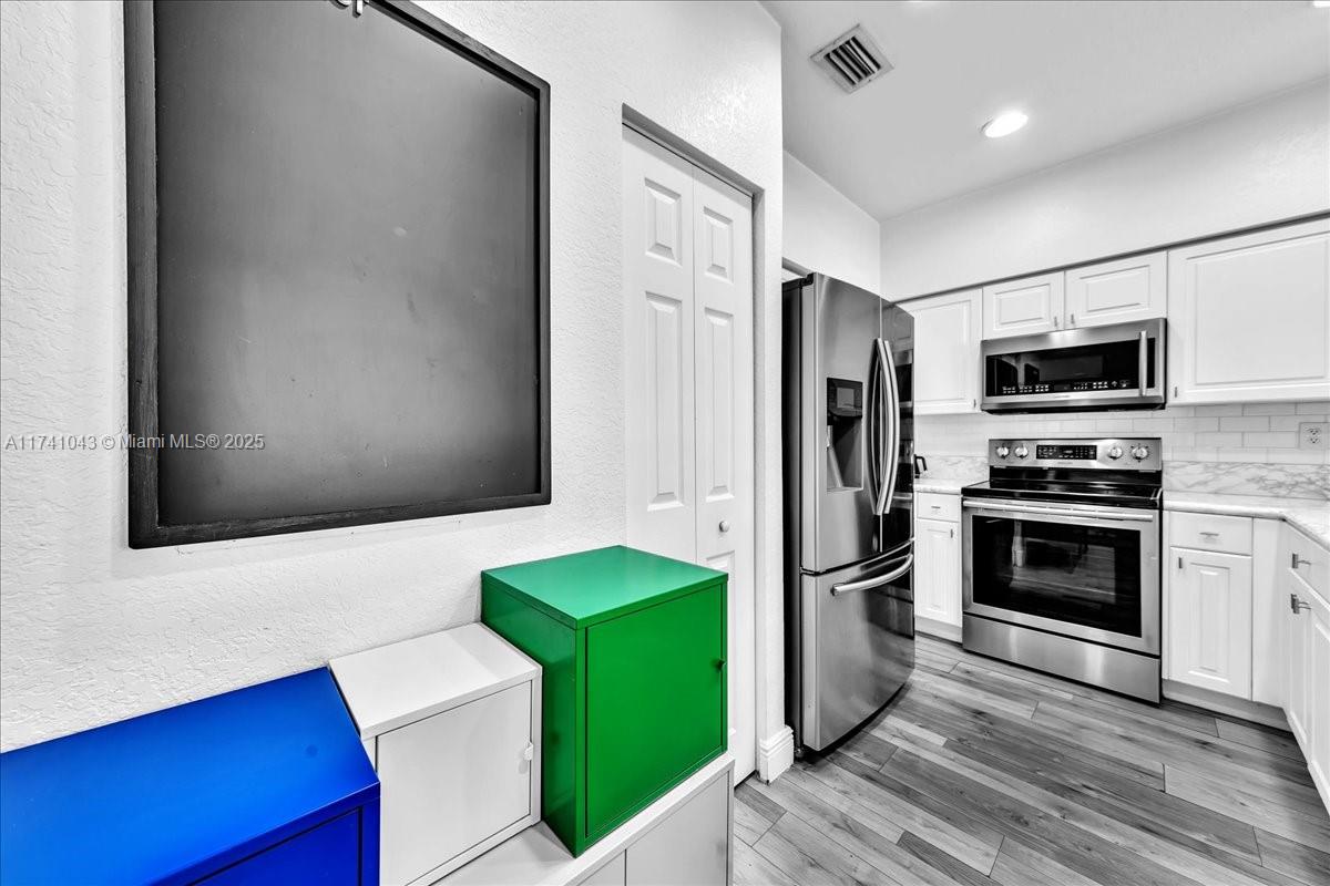 8381 Southwest 26 Th Street, Unit 103 Miramar, FL 33025 - Photo 13 of 62 a kitchen with a refrigerator stainless steel appliances wooden floor and cabinets