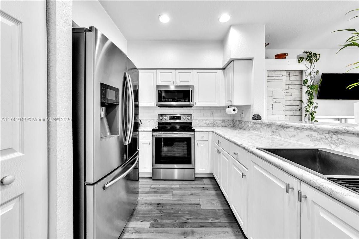 8381 Southwest 26 Th Street, Unit 103 Miramar, FL 33025 - Photo 15 of 62 a kitchen with stainless steel appliances granite countertop a refrigerator and a stove top oven