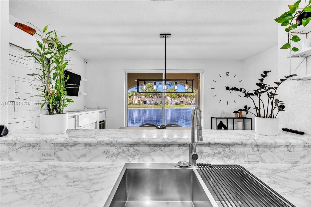 8381 Southwest 26 Th Street, Unit 103 Miramar, FL 33025 - Photo 20 of 62 a kitchen with granite countertop a sink a counter and a potted plant